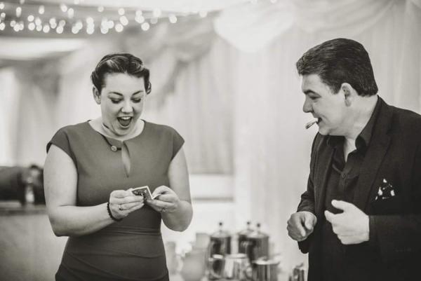 Wedding Magician Darren Brand  wows a lady with a surprised playing card appearing in her hand.