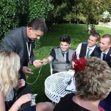 One of the UK’s leading magicians Darren Brand is at an outside table at a wedding  at Aston Hall in Sheffield. The sun is shining and they look amazed.