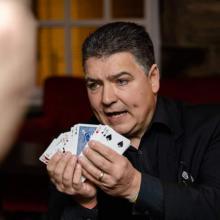 Wedding magician Darren Brand is displaying a pack of cards fanned our facing the audience with a single card back to front.